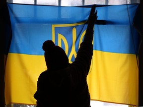 A person hangs a Ukrainian flag in the window of a residence in Winnipeg to show support for Ukraine on Saturday, March 5, 2022.  Russia has started a war and invaded Ukraine.