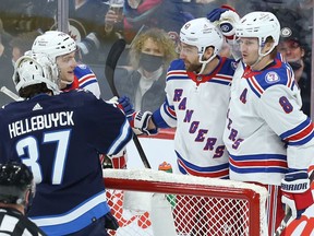 New York Rangers centre Barclay Goodrow (centre) celebrates his goal past Winnipeg Jets goaltender Connor Hellebuyck in Winnipeg with Jonny Brodzinski (left) and Jacob Trouba on Sunday, March 6, 2022.