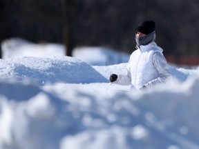A person wearing white runs along a path among large piles of snow in Winnipeg. Chris Procaylo/Winnipeg Sun