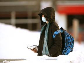 A person wears a mask while walking along a sidewalk in Winnipeg on Friday, March 11, 2022.