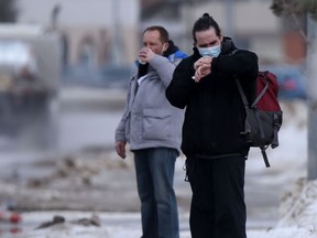 Two people standing on a sidewalk in Winnipeg on Tuesday, March 15, 2022.