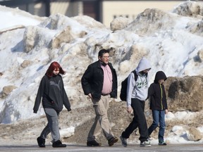 A group of people walk past a large pile of snow in Winnipeg.  Chris Procaylo/Winnipeg Sun