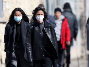 People wear masks while walking in public in Winnipeg on Friday, March 18, 2022.