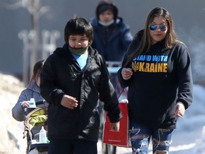 A group of people, one of whom is wearing a Stand With Ukraine shirt, walking in downtown Winnipeg on Saturday, March 19, 2022.
