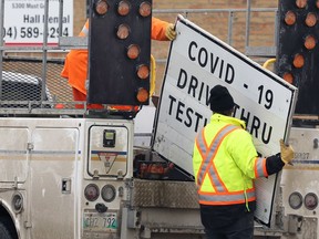 City workers remove signage for the COVID-19 testing site on Main Street in Winnipeg on Monday, March 21, 2022. There were 18 testing sites that were closed in the province as of March 20, while the vaccine site at RBC Convention Centre will be the last remaining one of its kind in the province as of March 26.