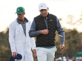 Scottie Scheffler and caddie Ted Scott walk off the 18th green after finishing their round during the third round of the Masters at Augusta National Golf Club on Saturday.