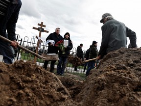 Maria, 13, holds a photograph of her father Yurii Alekseev, 50, a territorial defence member who according to his family was killed by Russian soldiers, as she mourns him with her godfather Igor Tarkovskii, 60, during his funeral, amid Russia's invasion of Ukraine, at the cemetery in Bucha, Kyiv region, Ukraine April 26, 2022.