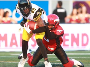 Tiger Cats Jalen Saunders (89) is brought down by Stamps defender Clante Evans during CFL action between the Hamilton Tiger Cats and the Calgary Stampeders in Calgary at McMahon Stadium Saturday, July 29, 2017.