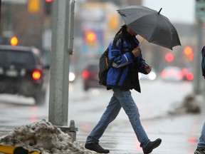 A person uses an umbrella while crossing a street in Winnipeg during heavy rain on  Saturday. April 23.
