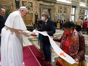 This photo taken and handout on April 1, 2022 shows Pope Francis receiving a stole from former national chief of Canada's Assembly of First Nations (AFN), Phil Fontaine (centre), during an audience to Canada's Indigenous delegations at the Vatican. Pope Francis on April 1 apologized for the decades of abuse at church-run residential schools in Canada and said he would visit the country in late July.