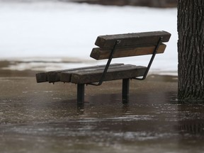 A park bench is surrounded by water in Winnipeg.  Chris Procaylo/Winnipeg Sun