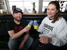 Operations manager Matthew Wolff (left) and general manager Camila Bellon toast with Red Eyes American Red Ale, a collaborative brew to raise funds for humanitarian relief in Ukraine, at the Torque Brewing taproom on King Edward Street in Winnipeg on Thursday, April 7, 2022.