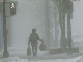 A person carries two bags while walking through heavy snow during a storm in Winnipeg on Wednesday. Chris Procaylo/Winnipeg Sun