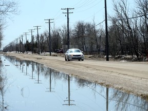 Overhead utility lines are reflected in a flooded ditch in Winnipeg. With more rain on the way, overland flooding is a concern in some areas.