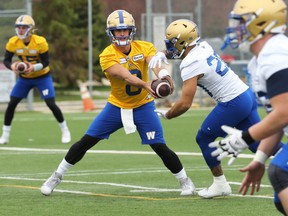 Quarterback Zach Collaros (left) hands off to Brady Oliveira during the first day of Winnipeg Blue Bombers training camp.