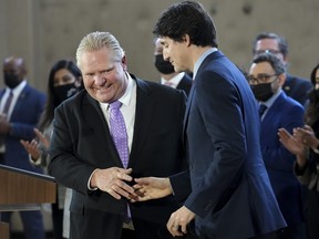 Prime Minister Justin Trudeau, right, shakes hands with Ontario Premier Doug Ford after reaching and agreement in $10-a-day child-care program deal in Brampton, Ont., on March 28, 2022.