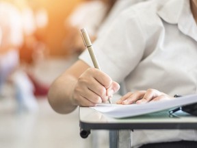 Exam with school student having a educational test, thinking hard, writing answer in classroom for university education admission and world literacy day concept