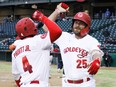 Logan Hill of the Winnipeg Goldeyes (right) celebrates with teammate Reggie Pruitt Jr. after hitting an eighth-inning home run on May 14, 2022, at Shaw Park in Winnipeg.