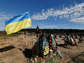 Ukraine's flag is seen beside new graves for people killed during Russia's invasion of Ukraine, at a cemetery in Bucha Kyiv region, Ukraine April 28, 2022.