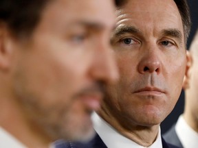Canada's Minister of Finance Bill Morneau looks at Prime Minister Justin Trudeau during a press conference in Ottawa on March 11, 2020.