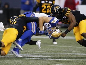 Winnipeg Blue Bombers' Drew Wolitarsky (82) gets tackled by Hamilton Tiger-Cats' Jovan Santos-Knox (45) and Simoni Lawrence (21) during the first half on Friday night.