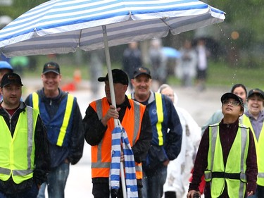 Rain falling from a large umbrella hits the hat of a volunteer for the 26th annual Cruisin' Down the Crescent fundraising event for the Rehabilitation Centre for Children on Wellington Crescent in Winnipeg on Sunday, June 12, 2022. Returning from a two-year break due to the COVID-19 pandemic, the event supports programs, equipment, technology and research for children and youth living with physical and developmental disabilities.