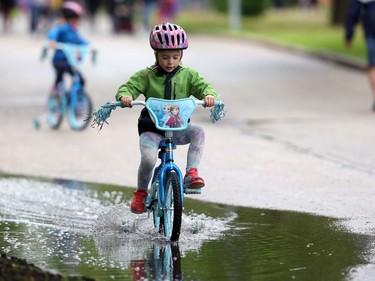 A girl pedals her bicycle through a puddle during the 26th annual Cruisin' Down the Crescent fundraising event for the Rehabilitation Centre for Children on Wellington Crescent in Winnipeg on Sunday, June 12, 2022. Returning from a two-year break due to the COVID-19 pandemic, the event supports programs, equipment, technology and research for children and youth living with physical and developmental disabilities. KEVIN KING/Winnipeg Sun/Postmedia Network