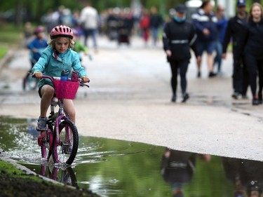 A girl pedals her bicycle through a puddle during the 26th annual Cruisin' Down the Crescent fundraising event for the Rehabilitation Centre for Children on Wellington Crescent in Winnipeg on Sunday, June 12, 2022. Returning from a two-year break due to the COVID-19 pandemic, the event supports programs, equipment, technology and research for children and youth living with physical and developmental disabilities.
