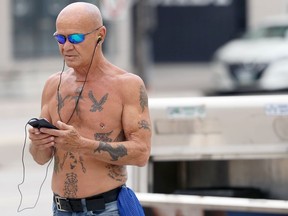 A tattooed man walks shirtless in downtown Winnipeg on Monday, June 13, 2022.