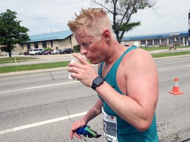 A runner takes water along Pembina Highway during the Manitoba Marathon in Winnipeg on Sunday, June 19, 2022.
