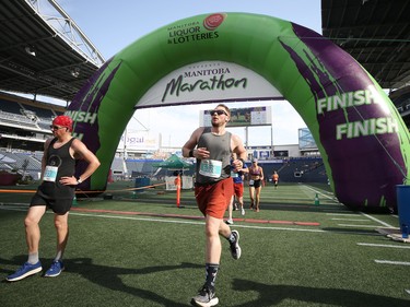 Half-marathon runners cross the finish line at IG Field during the Manitoba Marathon in Winnipeg on Sunday, June 19, 2022.