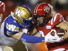 Winnipeg Blue Bombers' Adam Bighill stops Calgary Stampeders' Ante Milanovic-Litre during the second half of their CFL football game in Calgary, Saturday, Nov. 20, 2021.T
