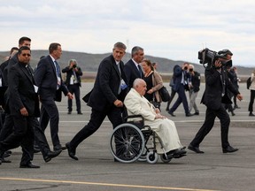 Pope Francis is pushed on a wheelchair as he arrives at Iqaluit International Airport, in Iqaluit, Nunavut, Friday, July 29, 2022.