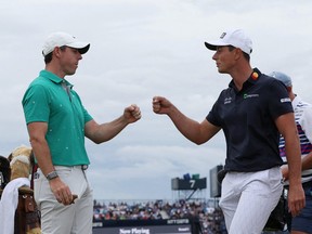 Northern Ireland's Rory McIlroy and Norway's Viktor Hovland celebrate on the 10th during the third round after scoring an eagle and a birdie respectively at the Open Championship in St Andrews, Scotland, July 16, 2022.