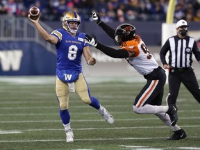Winnipeg Blue Bombers QB Zach Collaros (left) throws on the run with B.C. Lions DE Obum Gwacham in pursuit at IG Field in Winnipeg on Sat., Oct. 23, 2021. The Bombers take on the undefeated Lions on Saturday in Vancouver.