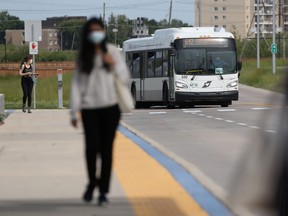 A person walks at a bus stop near where a transit funding announcement was made in Winnipeg on Thursday. July, 7.