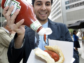 Michael Valenzuela squirts Heinz ketchup on to his hot dog during his lunch hour in downtown Calgary on May 14, 2010.   The Heinz ketchup company is changing their recipe after 40 years.