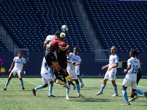 Members of Valour FC and FC Edmonton compete for a ball in the air.