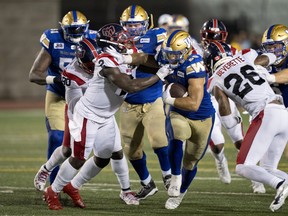 Winnipeg Blue Bombers running back Brady Oliveira fends off Montreal Alouettes linebacker Micah Awe during fourth quarter CFL football action in Montreal on Thursday, August 4, 2022.