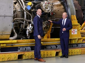 German Chancellor Olaf Scholz (right) and Siemens Energy Chairman Christian Bruch look at the Siemens gas turbine intended for the Nord Stream 1 gas pipeline in Russia at a Siemens Energy facility in Muelheim an der Ruhr, Germany, Wednesday, Aug. 3, 2022.