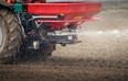 Tractor and fertilizer spreader in field.