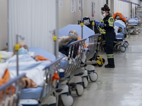 Paramedics transfer patients to the emergency room triage but have no choice but to leave them in the hallway due to an at capacity emergency room at the Humber River Hospital during the COVID-19 pandemic in Toronto on Tuesday, January 25, 2022.