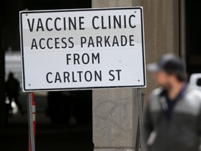 A person walks past a vaccine clinic sign in Winnipeg on Wednesday, Aug. 3. The Manitoba government announced Thursday that starting Friday at 9 a.m., all children aged six months to four years are eligible for COVID-19 vaccines.
