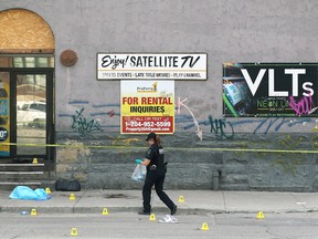 A forensics unit officer collects evidence after a fatal stabbing at the Mount Royal Hotel on Higgins Avenue in Winnipeg on Wed., Aug. 17, 2022. k