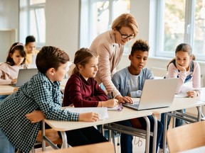 Group of elementary students having computer class with their teacher in the classroom.