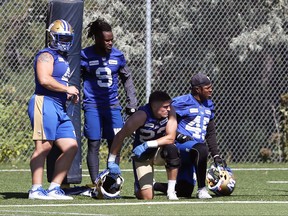 From left, Adam Bighill, Nick Taylor, Noah Hallett and Jamal Parker hang out under a goalpost during Bombers practice yesterday. The Bombers take on the Roughriders on Sunday.
