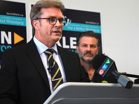 Winnipeg mayoral candidate Kevin Klein speaks as paramedic Ryan Woiden looks on during a press conference at Klein's campaign headquarters on Wednesday, Sept. 14.
