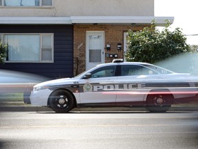 Traffic goes past a police cruiser sitting in front of a duplex on Logan Avenue near McPhillips Street in Winnipeg on Mon., Sept. 5, 2022.