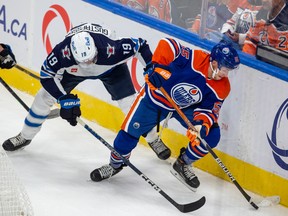 Edmonton Oilers Dylan Holloway (55) battles for the puck with Winnipeg Jets David Gustafsson (19) during first period preseason NHL action on Sunday, Sept. 25, 2022 in Edmonton.