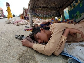 In this picture taken on Sept. 2, 2022, internally displaced flood affected children sleep under a charpai as they take refuge in Bolan district, Balochistan province.